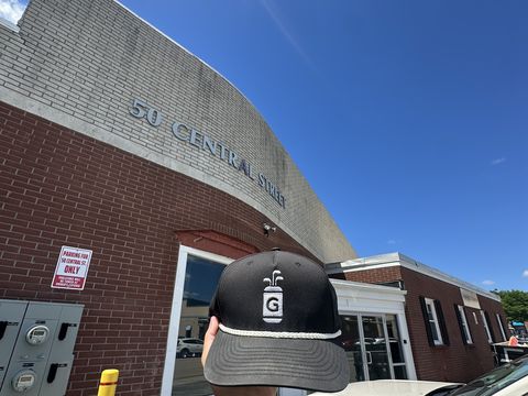 A Dr. Greens cap held up outside 50 Central Street
